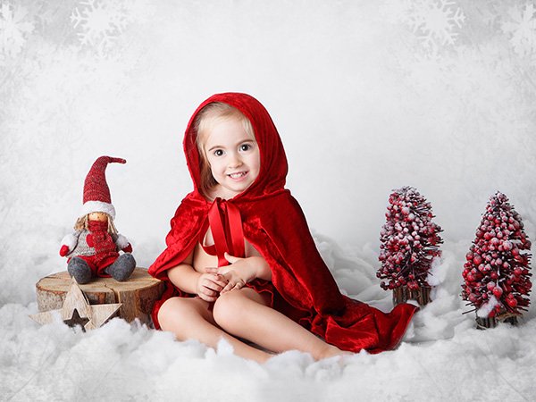 niña disfrazada de caperucita con troncos y elfos rojos navidad